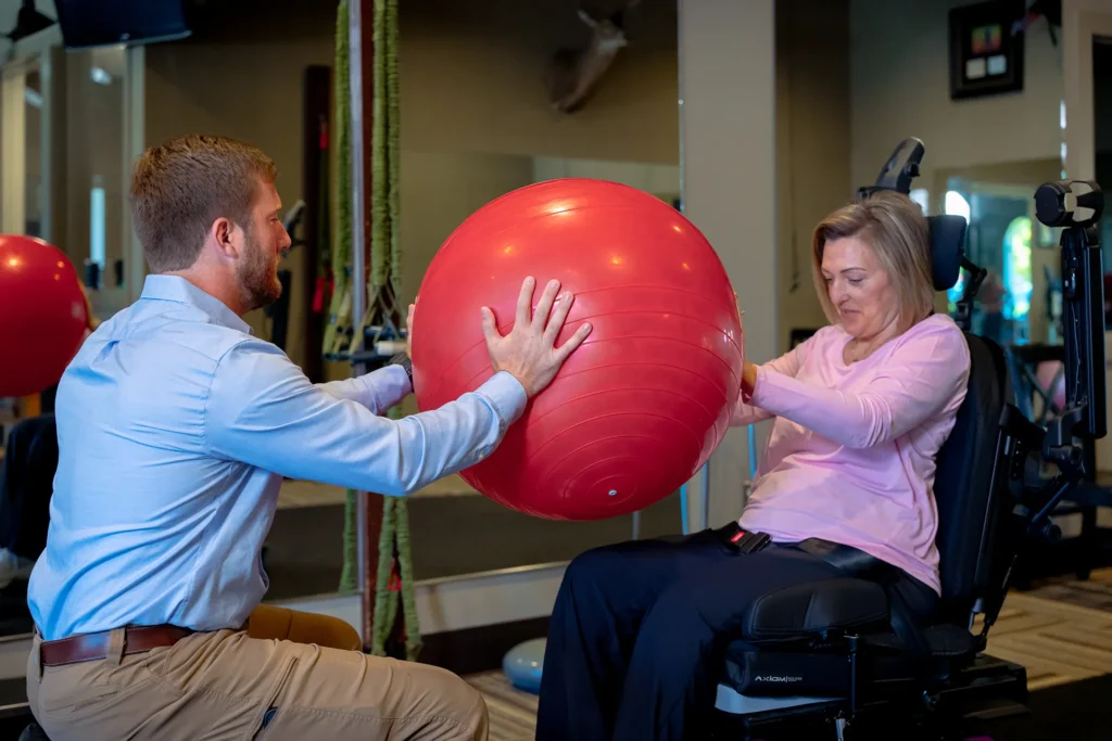 Physical Therapist helps rehabilitate woman using an exercise ball.